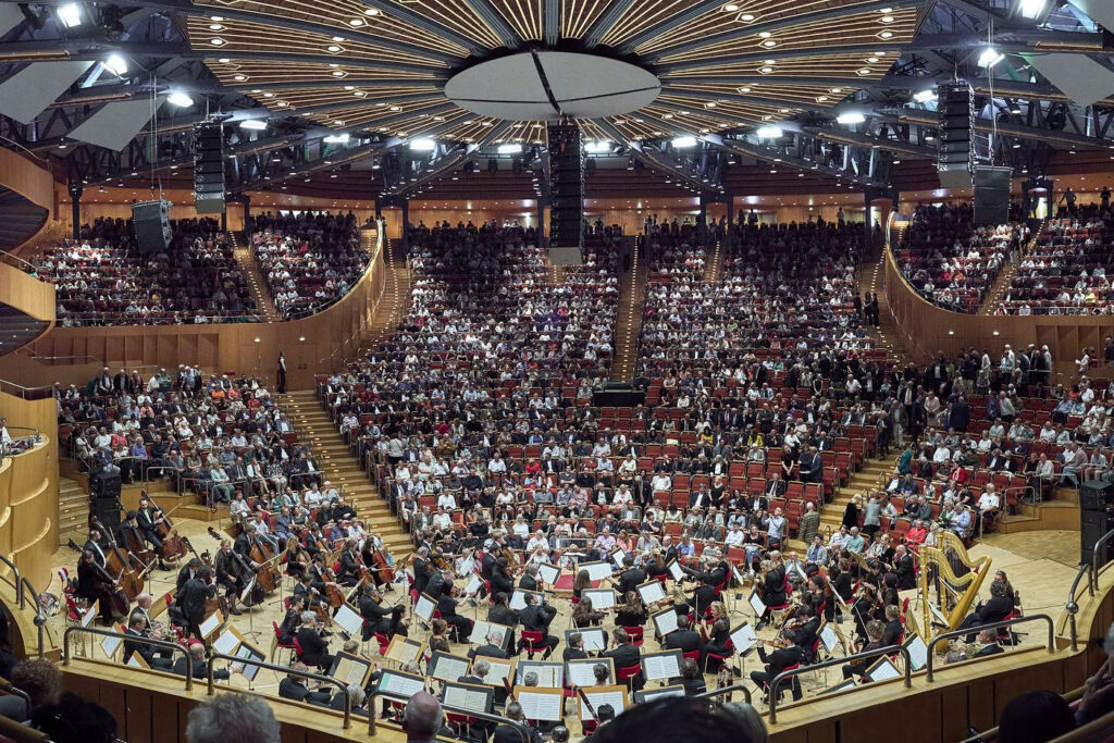 Der Saal der Kölner Philharmonie mit dem Gürzenich-Orchester in der Mitte und vielen Zuschauern im runden Zuschauerraum.
